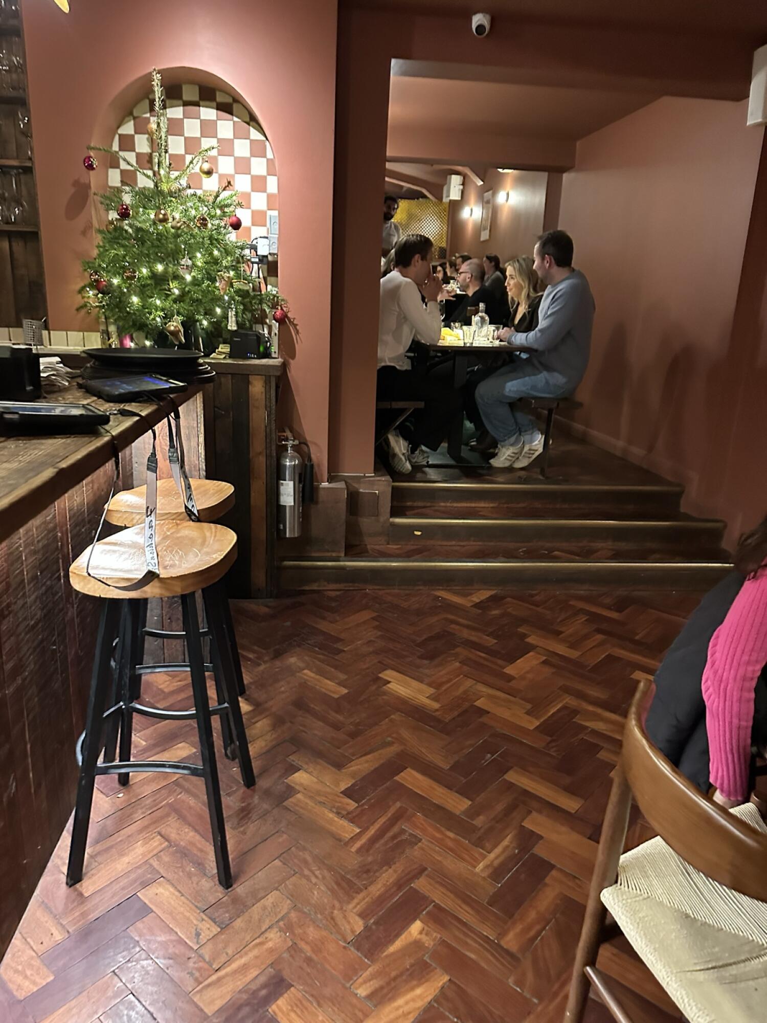 Two steps up after doorway. Tables and chairs in back space. High stools along left wall.