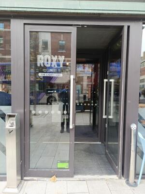 Glass doors with grey frames ahead. Push from handle at centre to open.