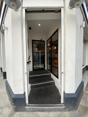 White framed archway. Steps up to entrance door behind. Black metal handrail on left.