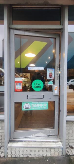 Grey metal framed glass door ahead. Push metal handle at right.