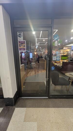 Dark metal-framed glass door. Push from handle on right to open.
