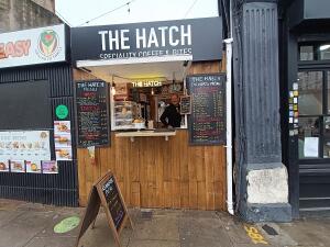 From street, facing venues. A-frame board on left. Display and counter at back.