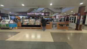 From shopping centre pathway facing venue. Open entrance to venue. Path to seating on right.