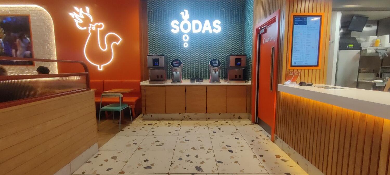 From pillar facing left. Booth on left. Drink dispenser at back center. Counter at front right.