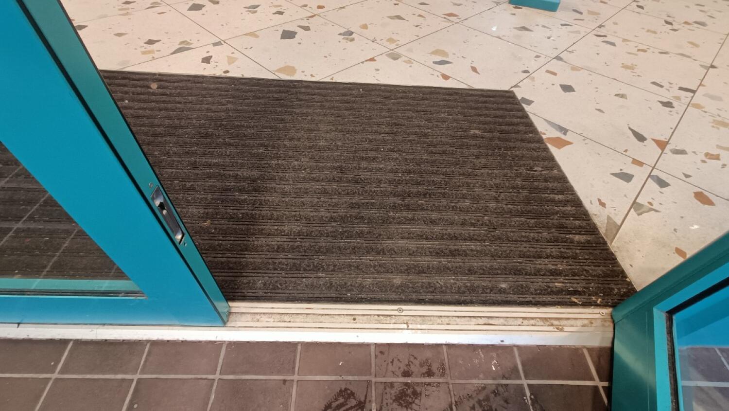 Small metal bump at foot of door followed by doormat.