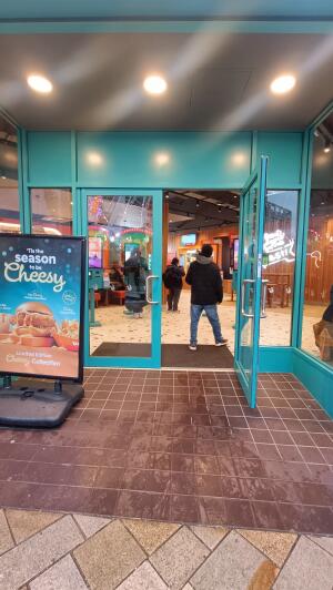 Green framed glass door to venue. Pull handle on centre to open. A-frame board on left.