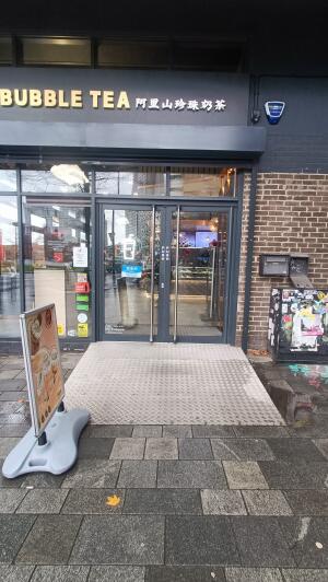 Black framed glass door to venue. Push handle on centre to open. A-frame board on left.
