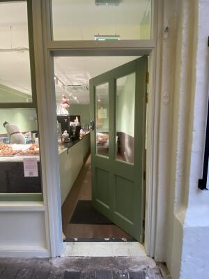Green door with glass panelling. Push from left to open.