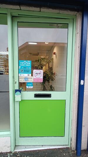 Green panelled glass door to venue. Push handle on left to open.