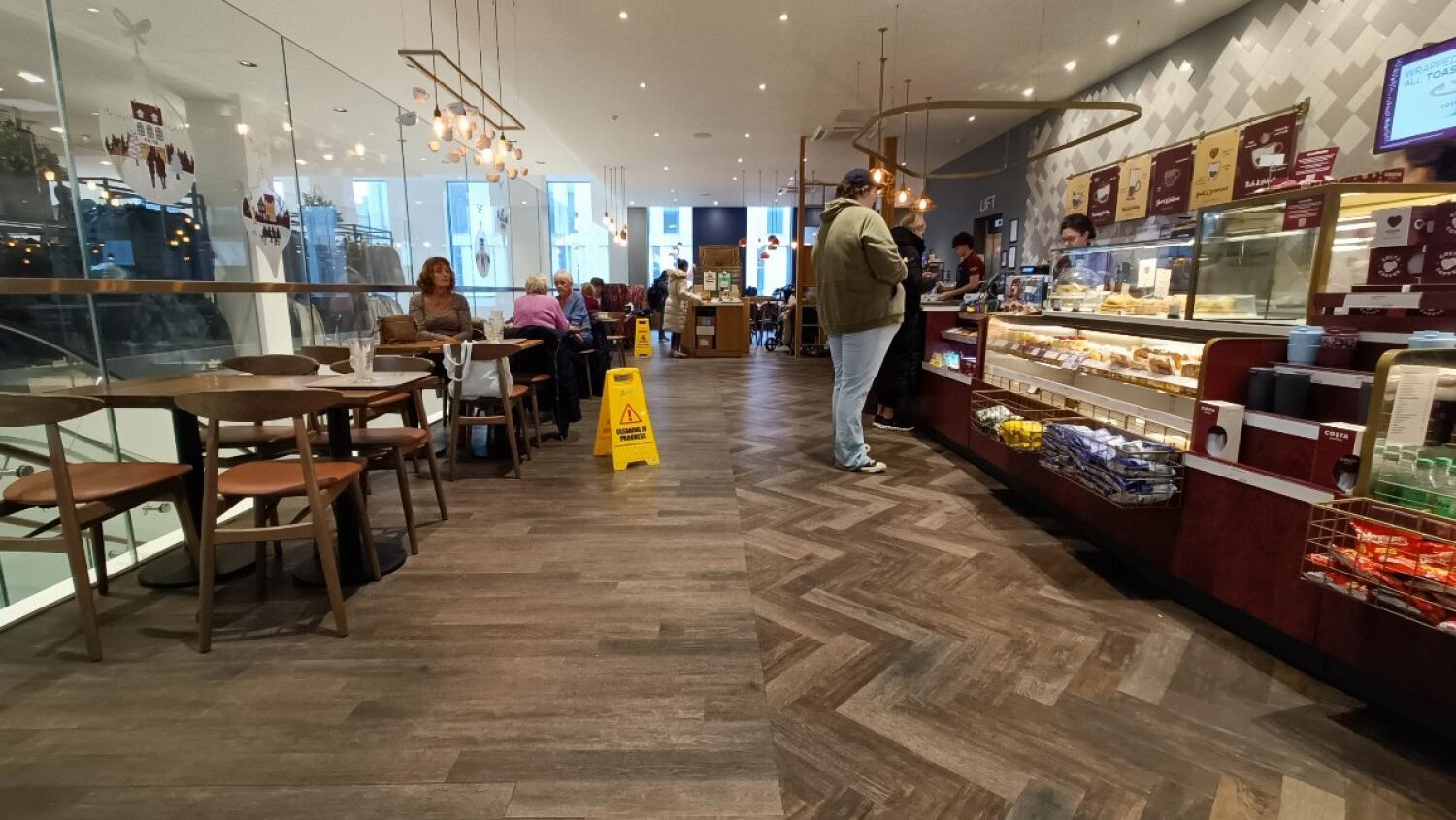 From entrance facing left. Chairs and tables along left. Condiment station at back. Counter along right.