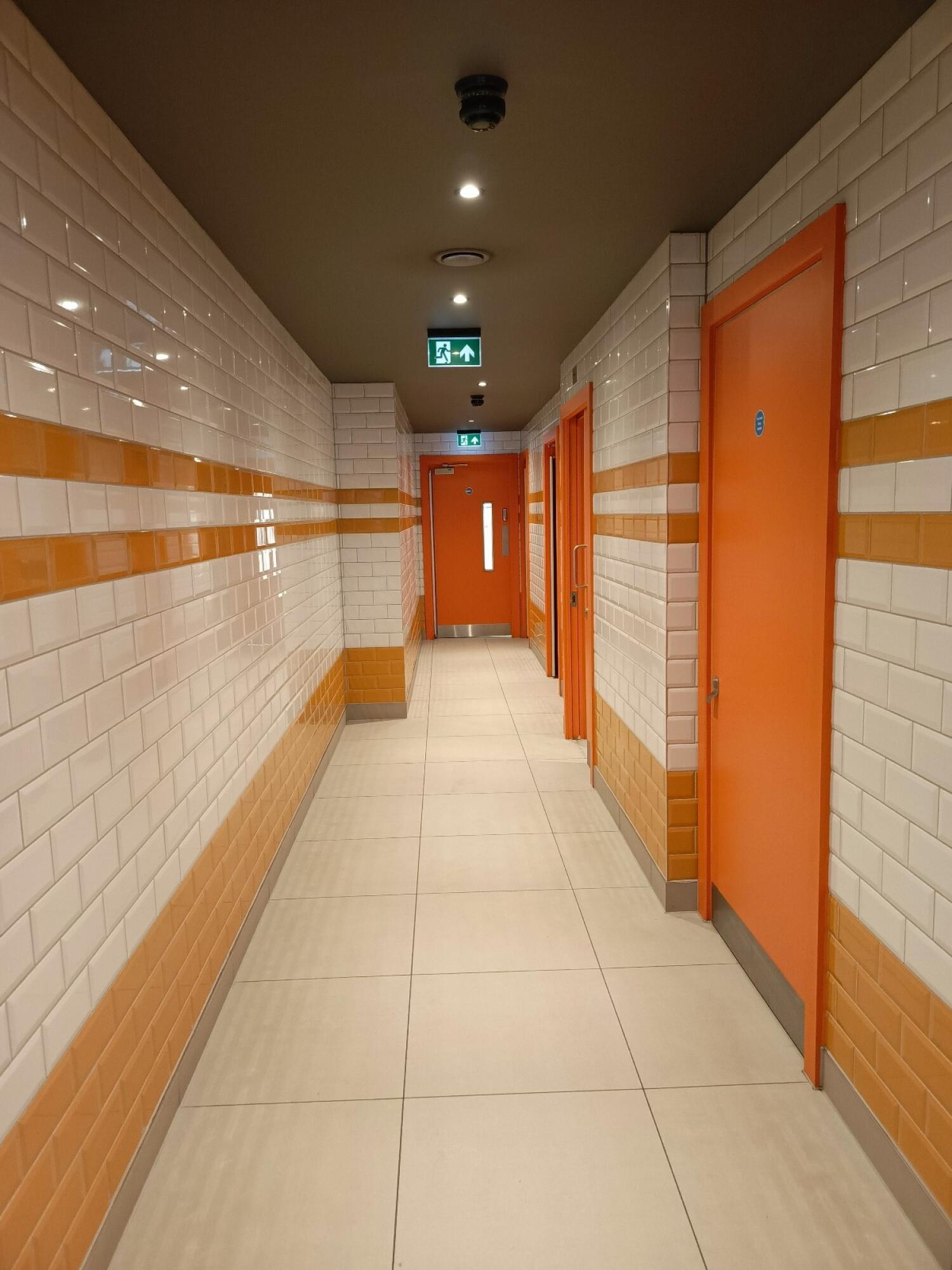 From archway facing straight. Path ahead. Doors along right.