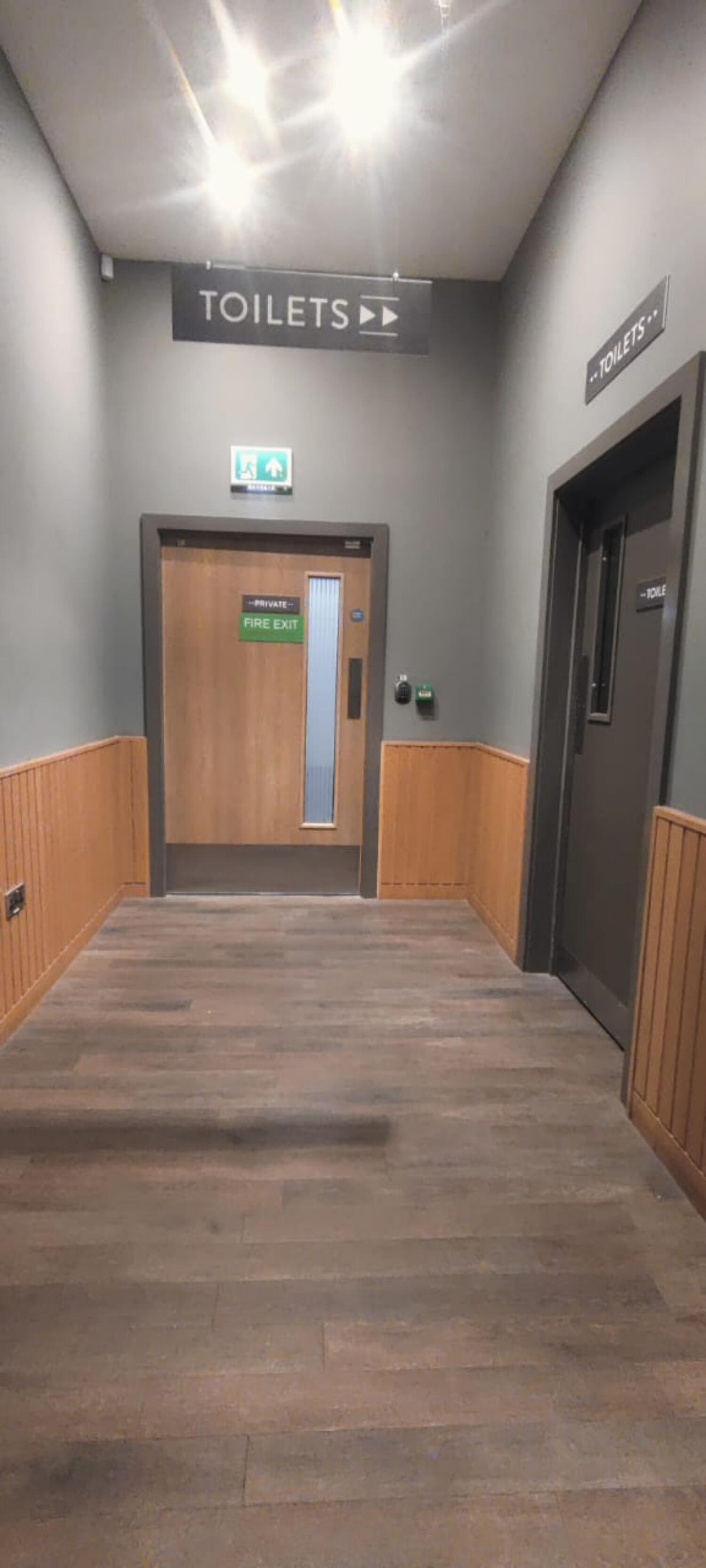 From end of path facing straight. Fire exit door ahead. Toilet door on first right.