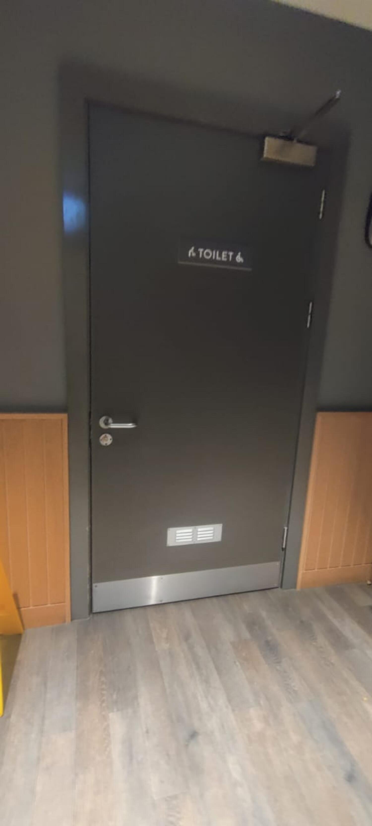 From first door facing straight. Grey metal door ahead. Twist handle at left.