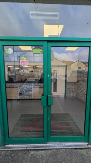 Green metal-framed glass doors. Push from handles at centre to open.