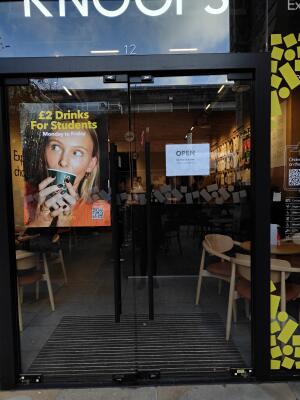 Black framed double glass doors ahead. Push black handle on centre to open.