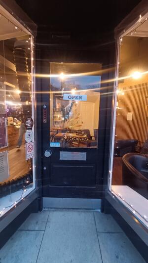 Black panelled glass door to venue. Push handle on left to open.