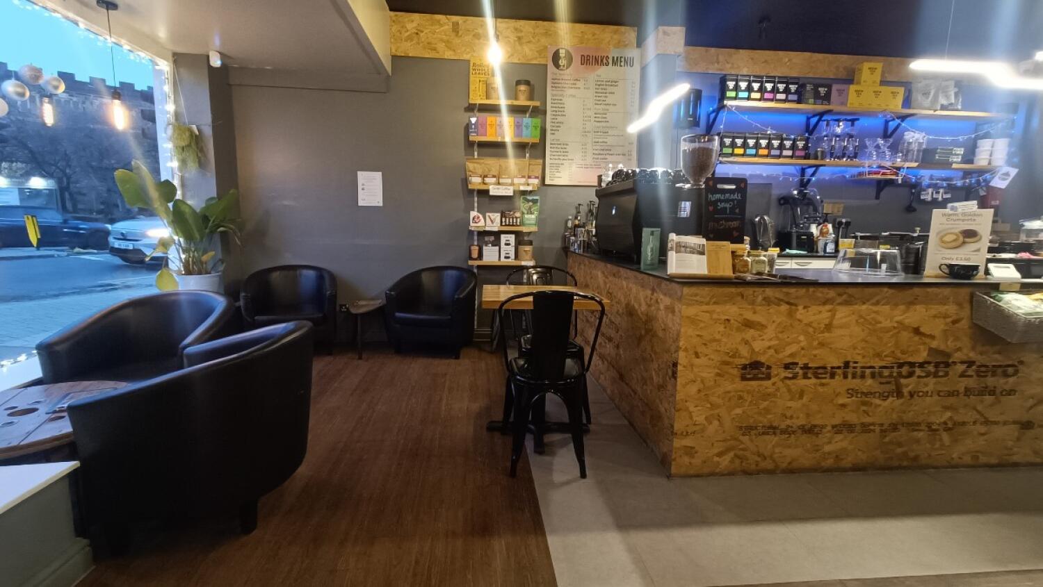 From entrance facing left. Armchair and table on left and back. Table and chair in centre. Counter along back right.