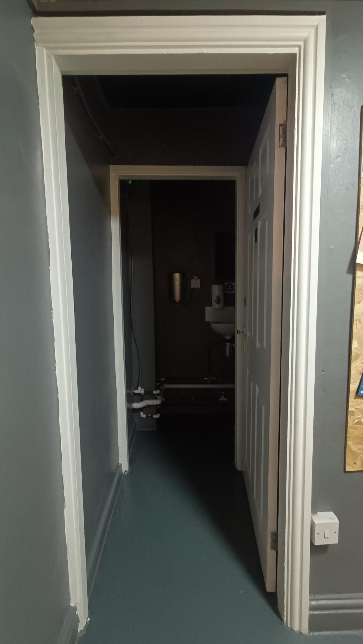 From archway facing left. White toilet door ahead. Push handle on left to open.