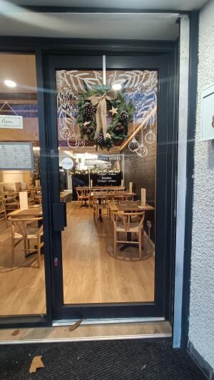 Black framed glass door to venue. Push handle on left to open.