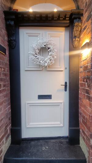 Black framed white door to venue. Push handle on right to open.