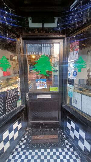 Black panelled glass door to venue. Push handle on left to open.