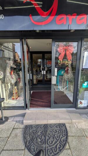 Glass doors with dark metal frame. Push from handles at centre to open.