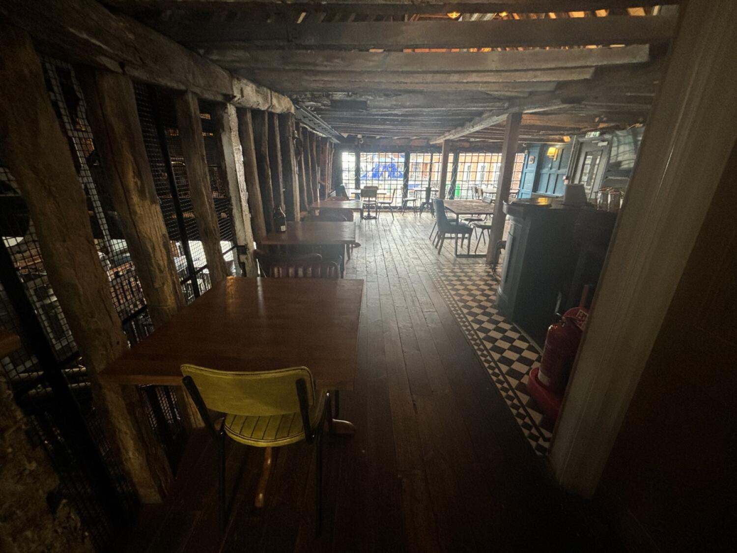 From top of stairs facing left. Tables and chairs on left. Path ahead to seating. Bar counter on right.