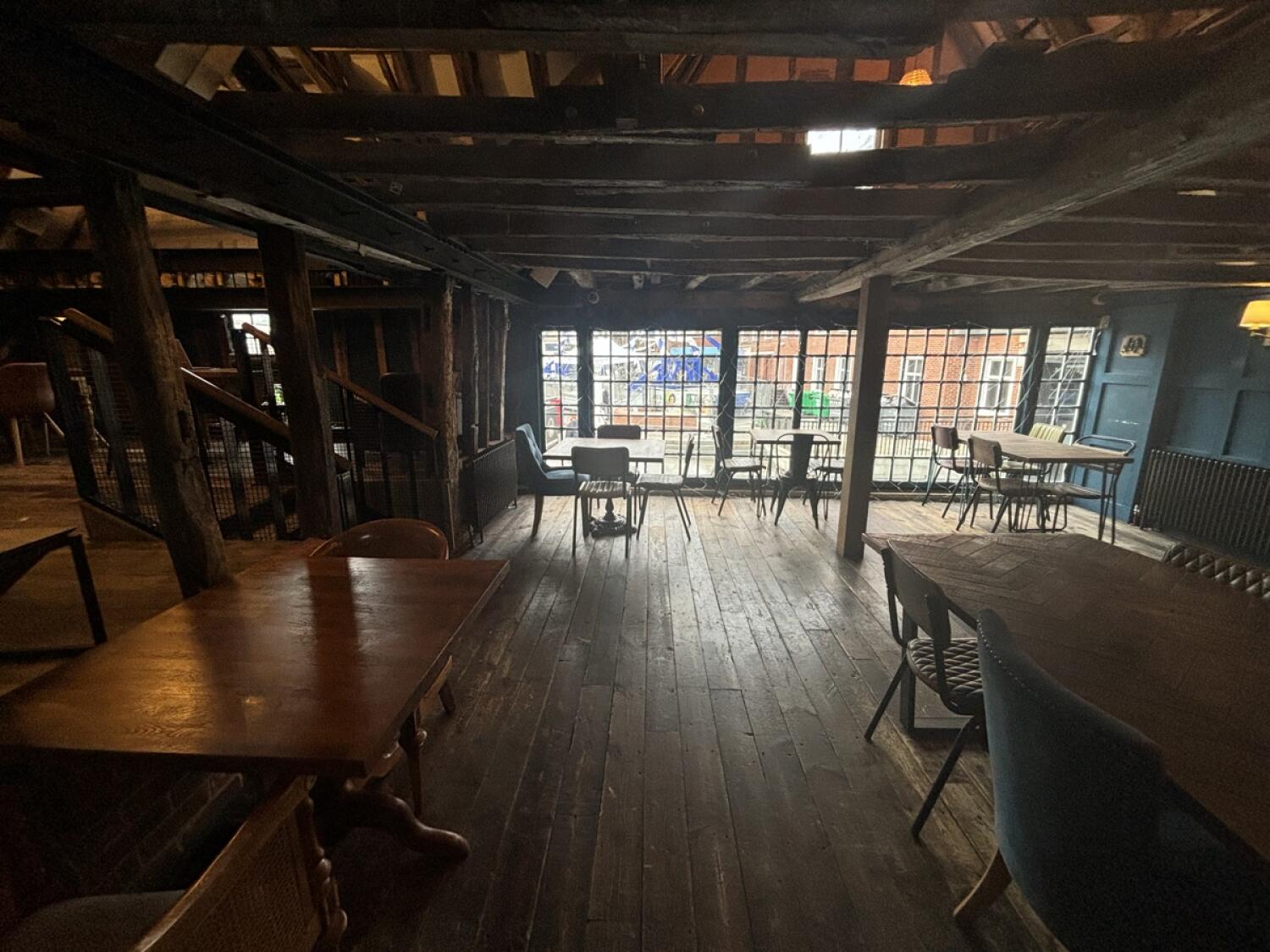 From bar counter facing straight. Tables and chairs on left, right and back. Path ahead to side area at back left.
