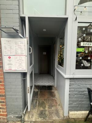 Grey framed glass door ahead. Pull handle on right to open. Inbuilt ramp slopes up to door.