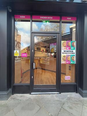 Glass door with black, metal frame. Push from handle on left to open.