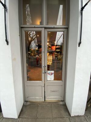 Grey framed glass door. Pull silver metal handle from centre to open.
