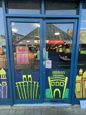 Blue framed glass doors ahead. Push from centre to open.