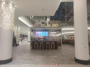 From mall corridor facing venue. Pillars on both sides. Archway to venue ahead. Venue at back.
