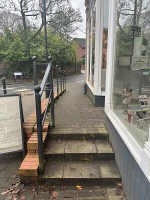 Three steps up to path heading to entrance. Handrail along left.