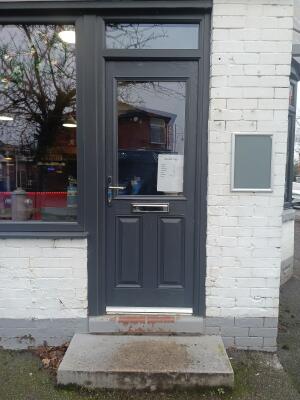 Glass door with grey frame ahead. Push from handle on left to open.
