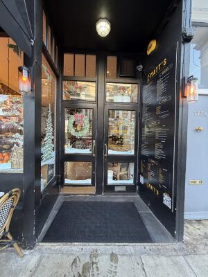Black wooden archway ahead. Glass doors with black wooden frames at back. Pull from center to open.