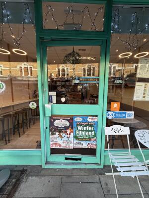 Glass door with green metal frames ahead. Push from left to open.