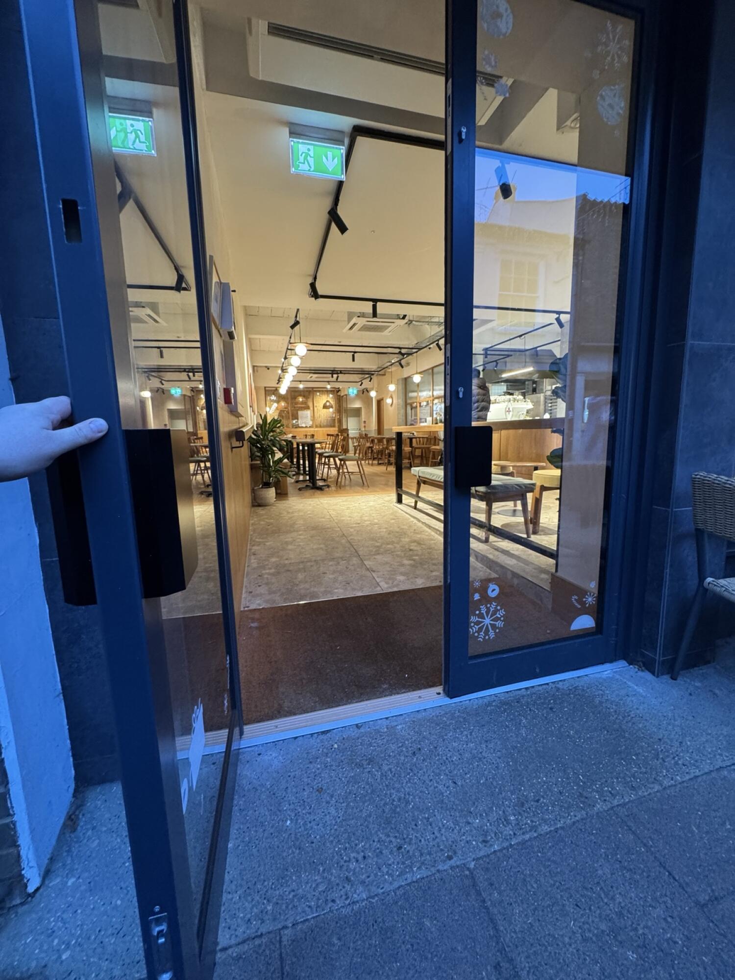 Dark metal-framed glass door. Pull from handle on left to open.