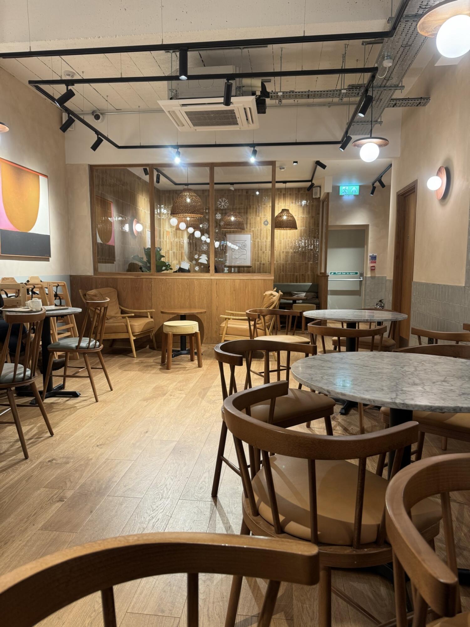 Tables and chairs along left. Round tables with chairs in centre. Small tables with chairs at back.