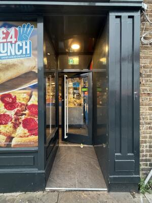 Archway ahead. Glass door with black metal frames at back. Push from left to open.