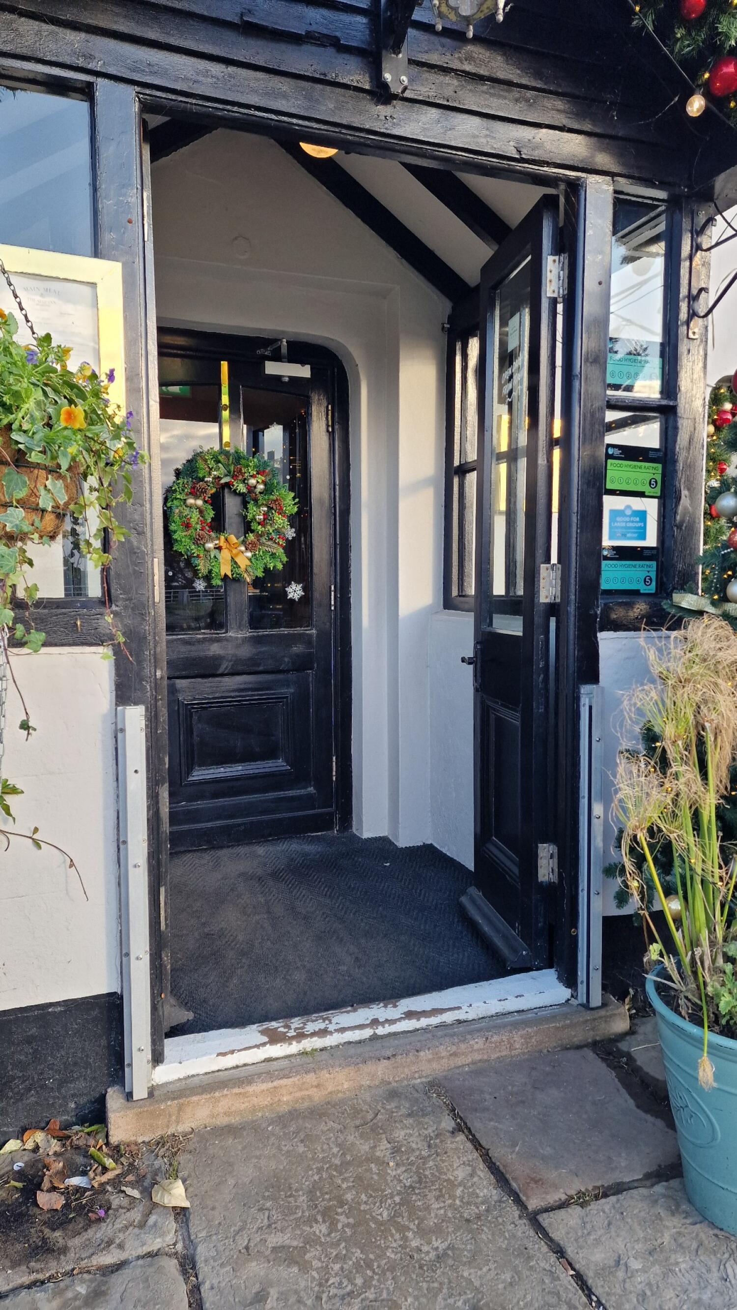 Black wooden door with glass panels. Pull from handle on left to open.