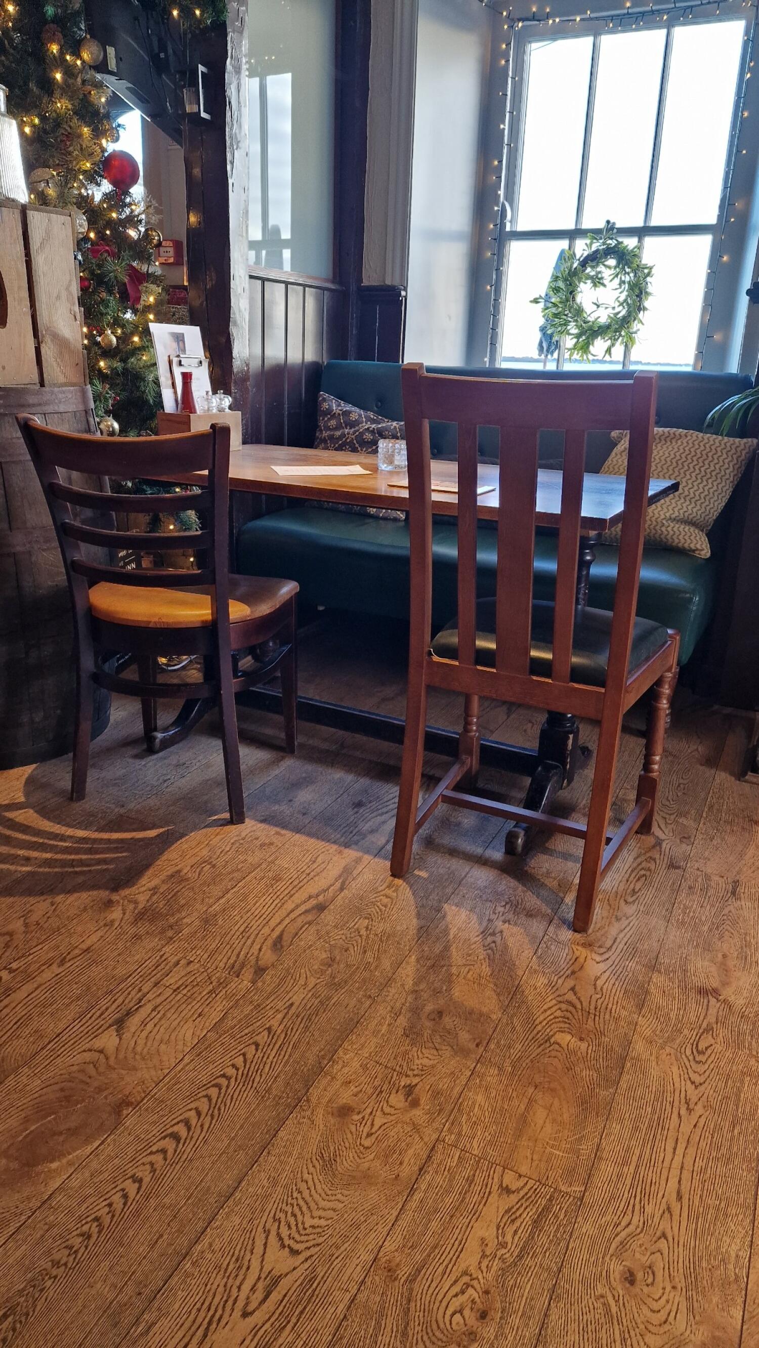 Half booth along back wall. Two chairs opposite booth. Table in-between chairs and booth.