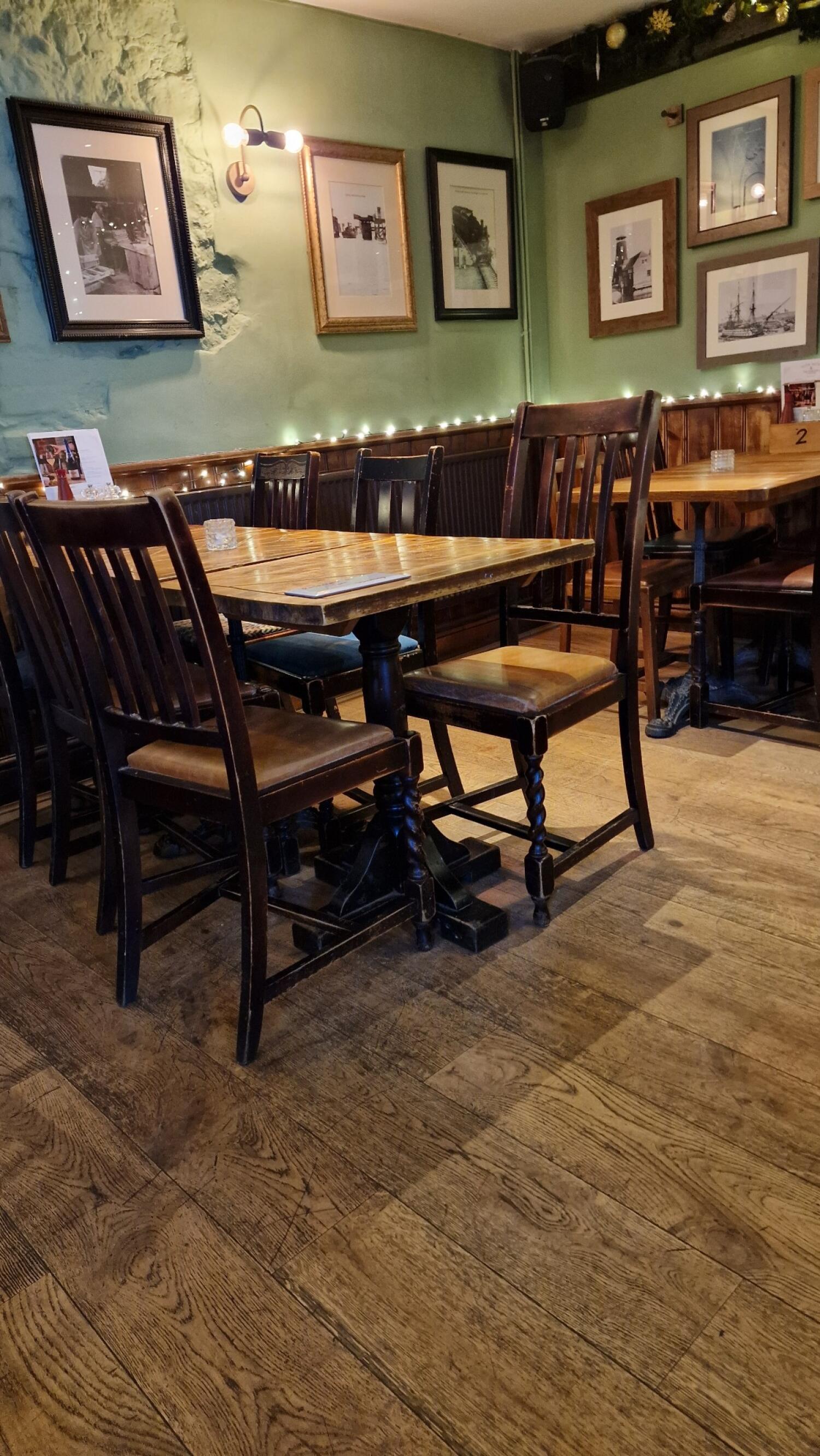Tables and chairs along left. More tables and chairs to right. Bench seating runs along back wall.