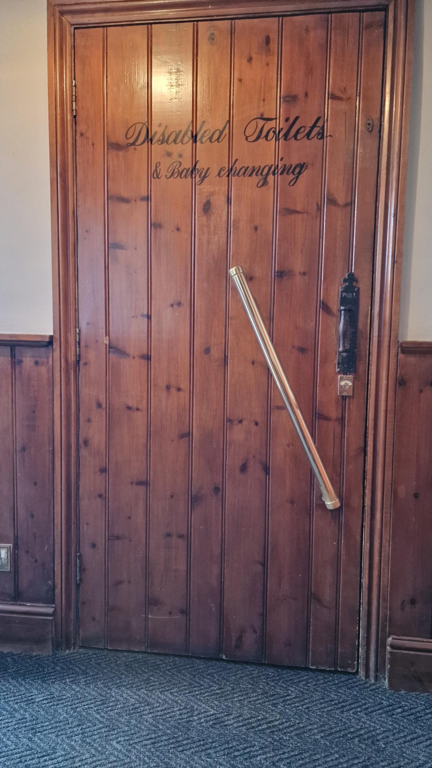 Wood-panelled door with grab rail in centre. Pull from handle on right to open.