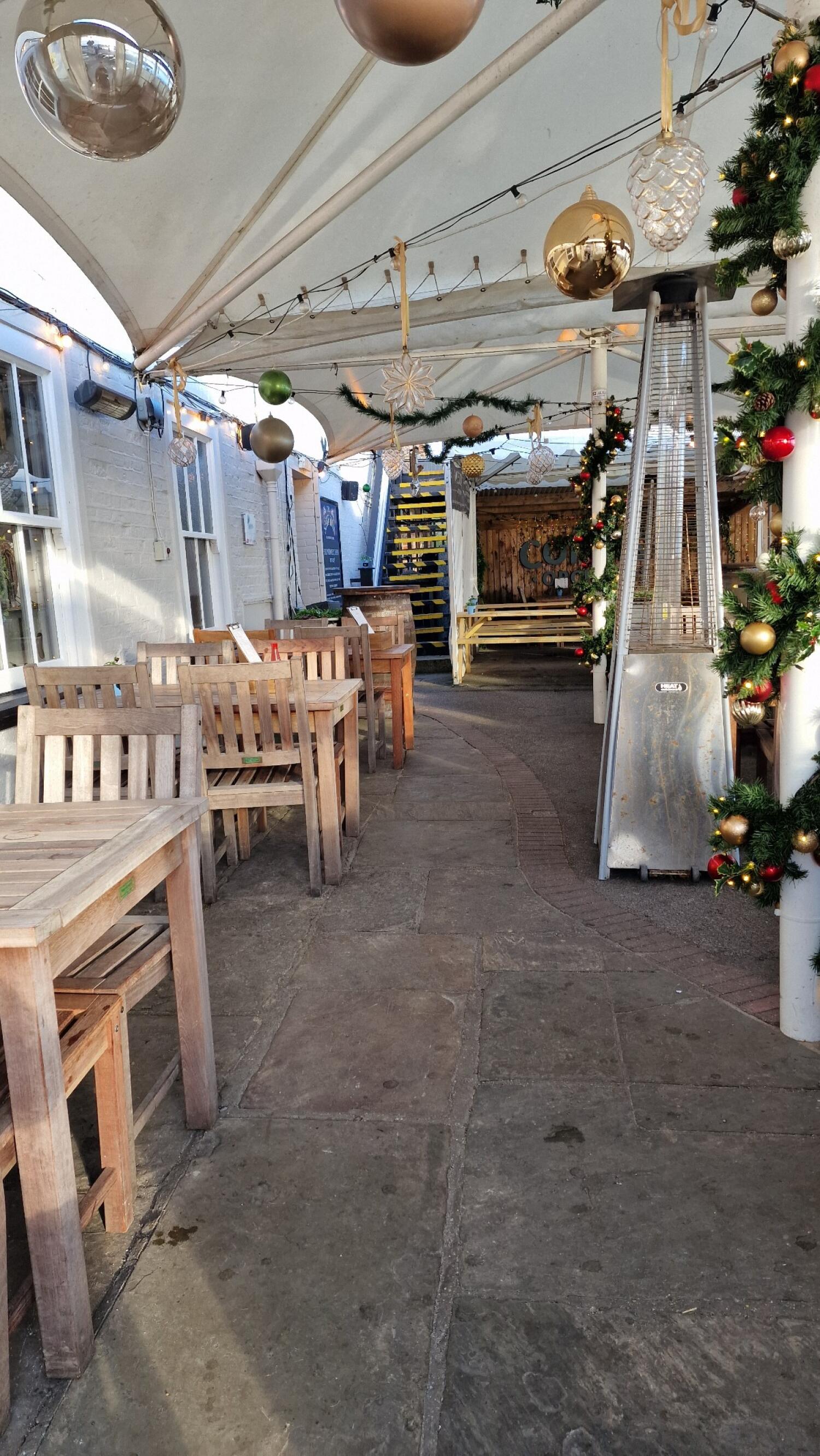 Tables and chairs along left. Path curves to stairs at back. Outdoor heater along right.
