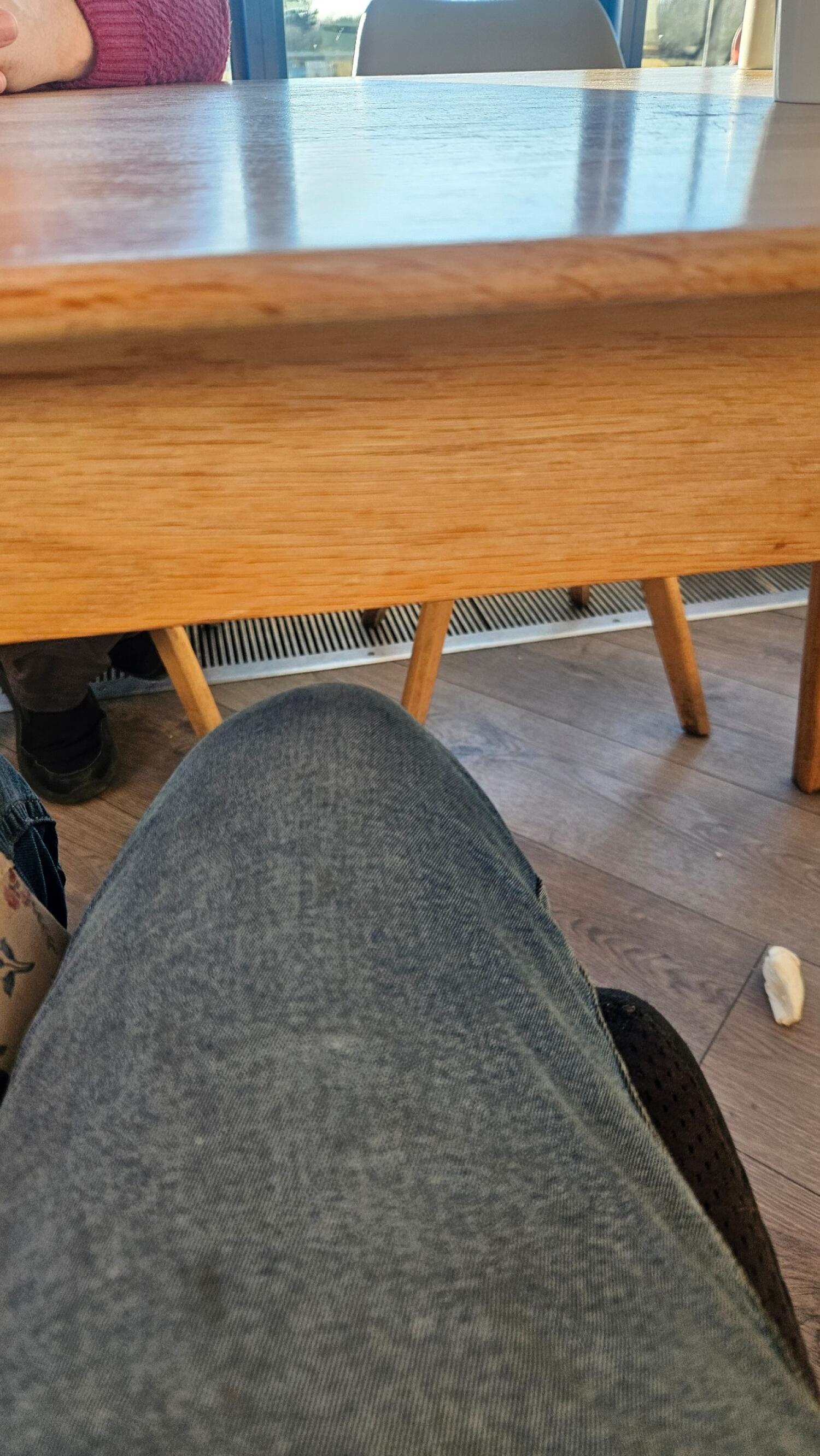 Wooden table with angled legs. Chair visible behind table.