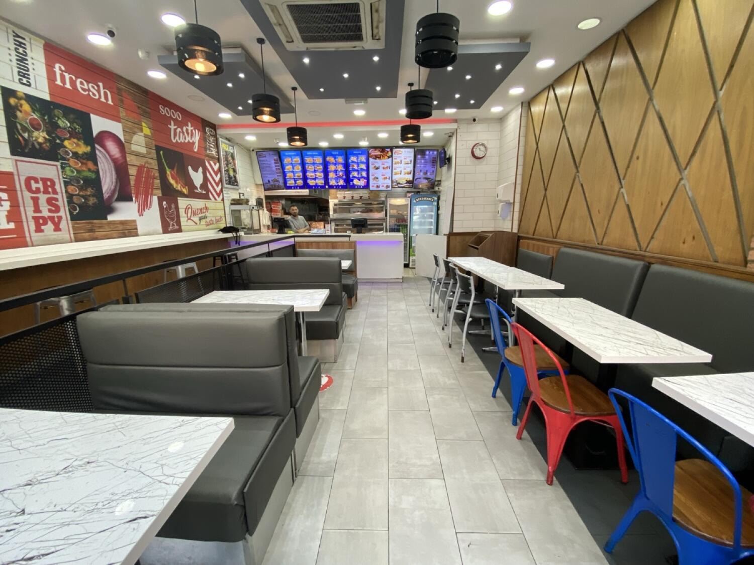 From start of half booths facing left. Booths on left. Half booths, tables and chairs along right. Counter at back.