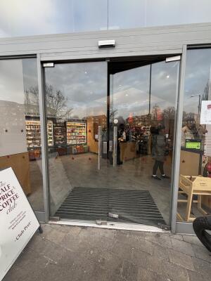 Glass doors with grey metal frames ahead. Push from center to open.