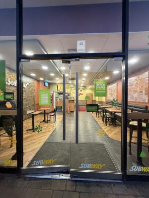 Glass doors with grey metal frames ahead. Push from center to open.