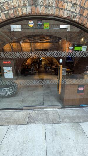 Glass door with patterned decals and wooden handle on right. Push from handle on right to open.